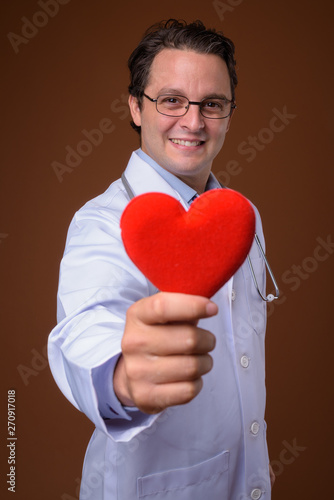 Portrait of Italian man doctor against brown background