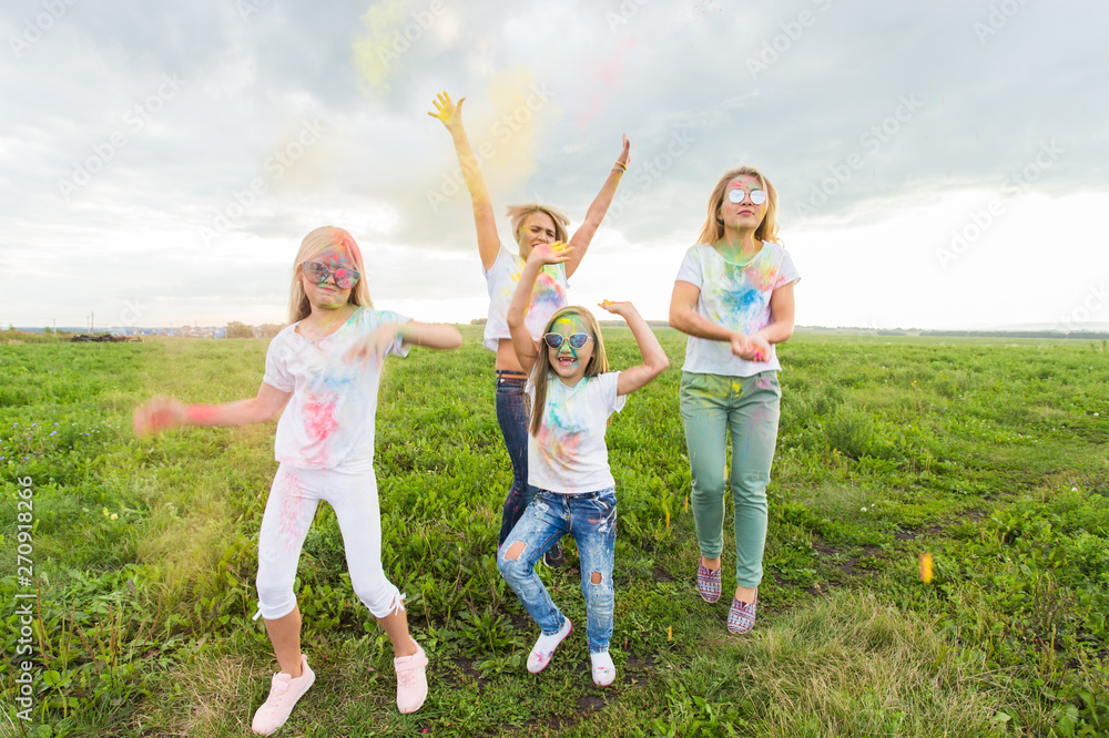 Holi festival, holidays and happiness concept - young teens and women in colors have fun outdoor