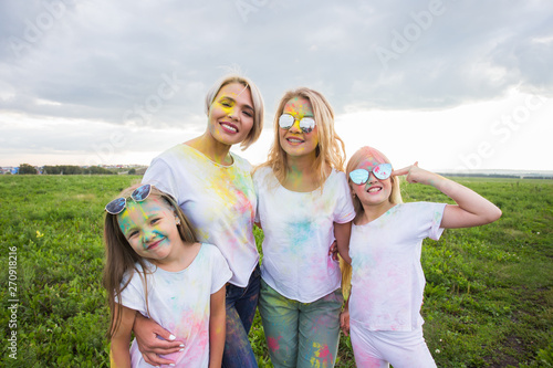 Holi festival, holidays and happiness concept - young teens and women in colors have fun outdoor