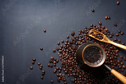 Turkish coffee pot, wooden spoon and beans on dark background with copy space.