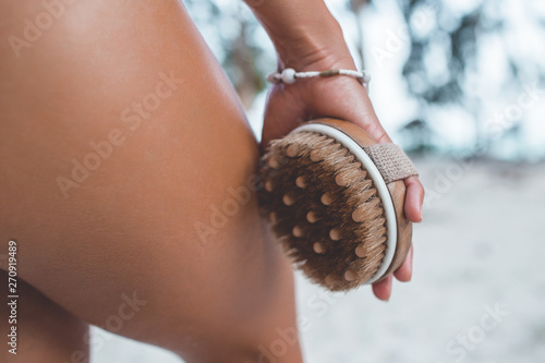 фотографія Young woman in tropical paradise is holding brush in hands antucellulite treatment