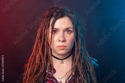 Portrait of young woman with dreadlocks over the dark background