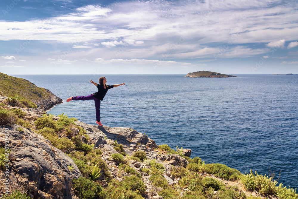 Obraz premium Young woman dancing and enjoying beautiful view. Kalymnos Island, Greece.
