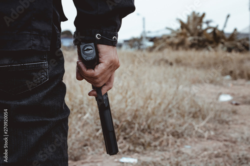 Killer holding a gun side him , cropped shot of man holding gun in hand.