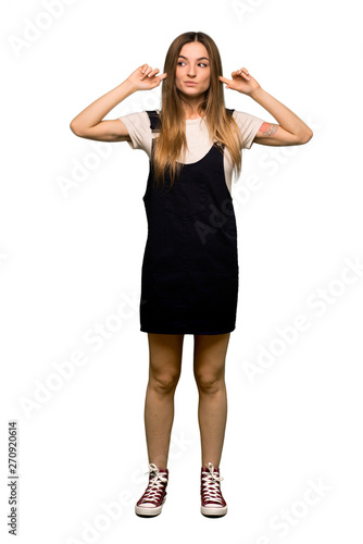 Full body Young pretty woman covering both ears with hands on isolated background © luismolinero