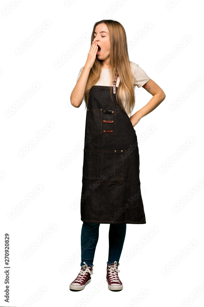 Full body Young woman with apron yawning and covering wide open mouth with hand on isolated background Full body Young woman with apron yawning and covering wide open mouth with hand on isolated background