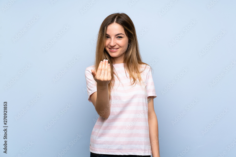 Young woman over isolated blue background inviting to come with hand. Happy that you came Young woman over isolated blue background inviting to come with hand. Happy that you came