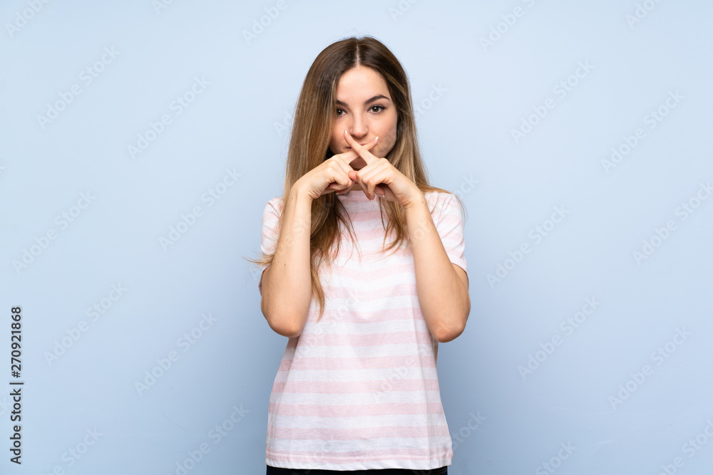 Young woman over isolated blue background showing a sign of silence gesture Young woman over isolated blue background showing a sign of silence gesture