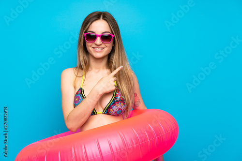 Young woman in bikini in summer holidays pointing to the side to present a product