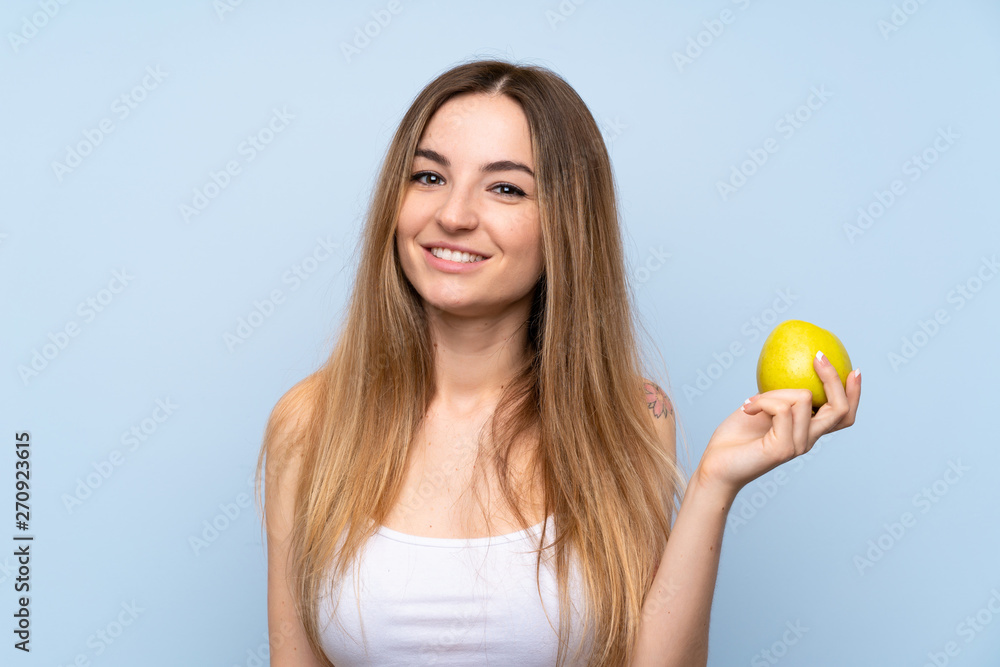 Young woman over isolated blue background with an apple Young woman over isolated blue background with an apple