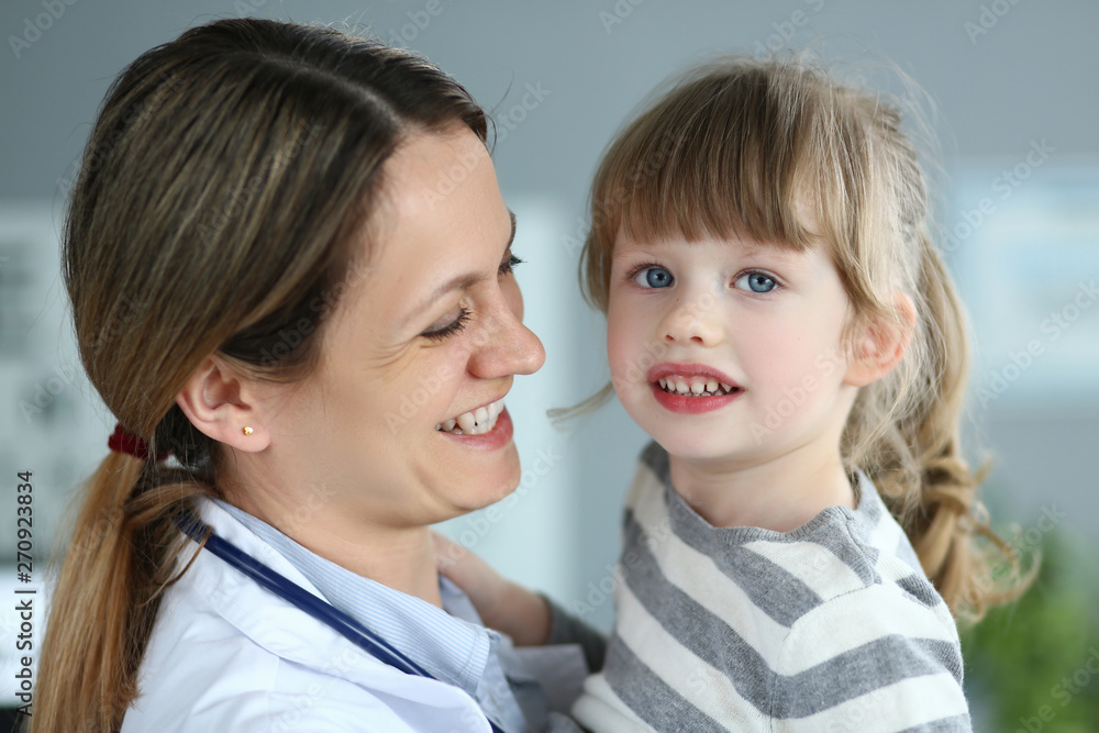 Paediatric doctor holding and hugging little cute girl patient Paediatric doctor holding and hugging little cute girl patient