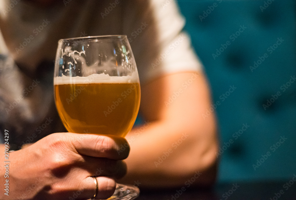 man's hand holds a glass of beer in bar