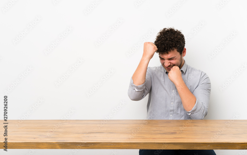 Young man with a table celebrating a victory Young man with a table celebrating a victory