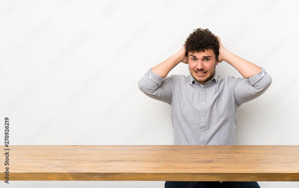 Young man with a table frustrated and takes hands on head Young man with a table frustrated and takes hands on head