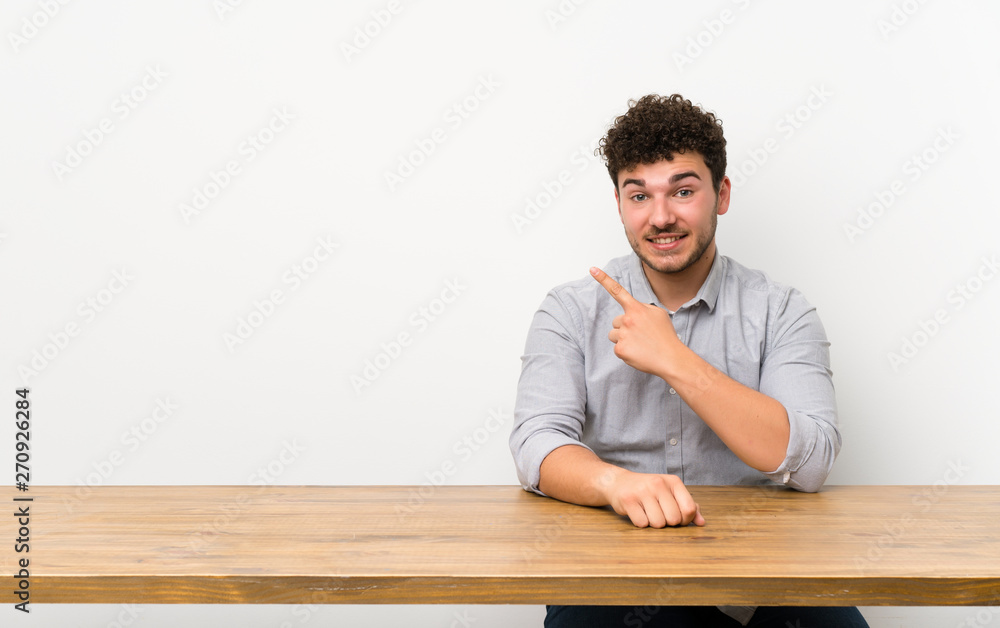 Young man with a table pointing to the side to present a product Young man with a table pointing to the side to present a product
