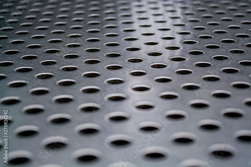 Background or texture from a gray and monophonic metal surface with symmetric and round openings.