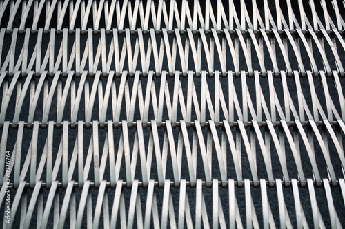 Background or texture on a gray wall a lattice from metal a wire which intertwine among themselves. Hooks and loops. Geometry of lines.