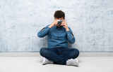 Young man sitting on the floor holding a camera