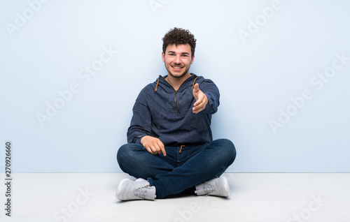 Young man sitting on the floor shaking hands for closing a good deal © luismolinero