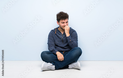 Young man sitting on the floor having doubts © luismolinero