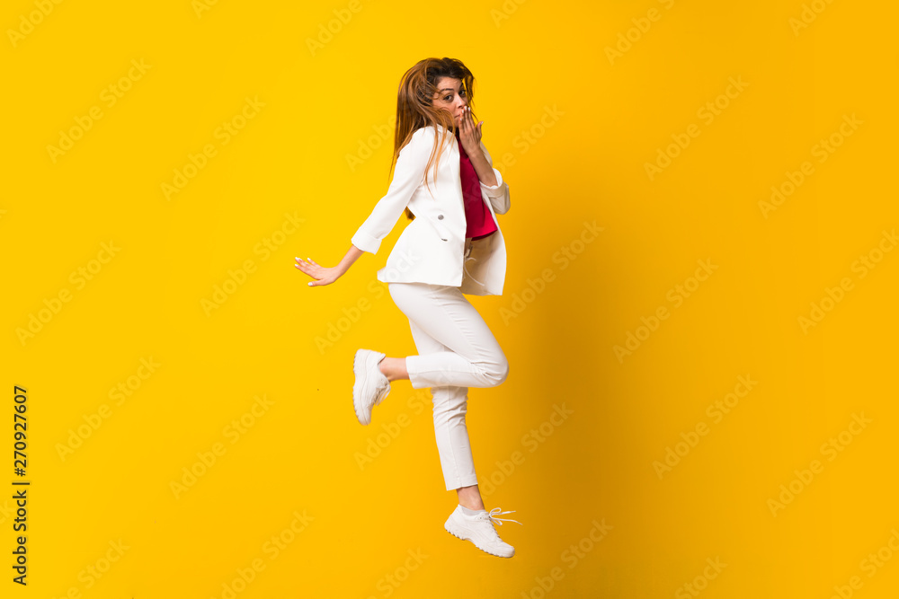 Young woman jumping over isolated yellow wall