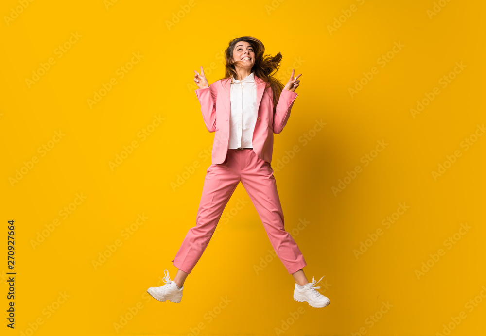 Young woman jumping over isolated yellow wall