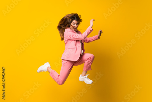 Fototapeta Naklejka Na Ścianę i Meble -  Young woman jumping over isolated yellow wall