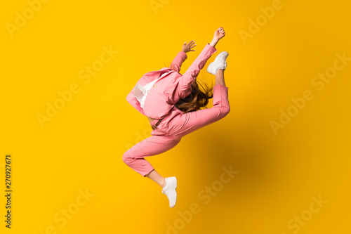 Young woman jumping over isolated yellow wall photo