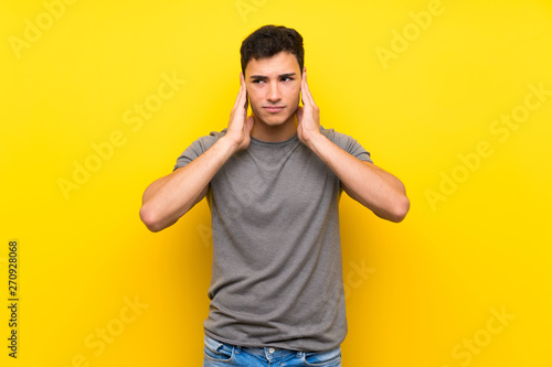 Handsome man over isolated yellow wall frustrated and covering ears