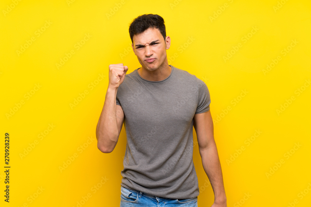 Handsome man over isolated yellow wall with angry gesture Handsome man over isolated yellow wall with angry gesture