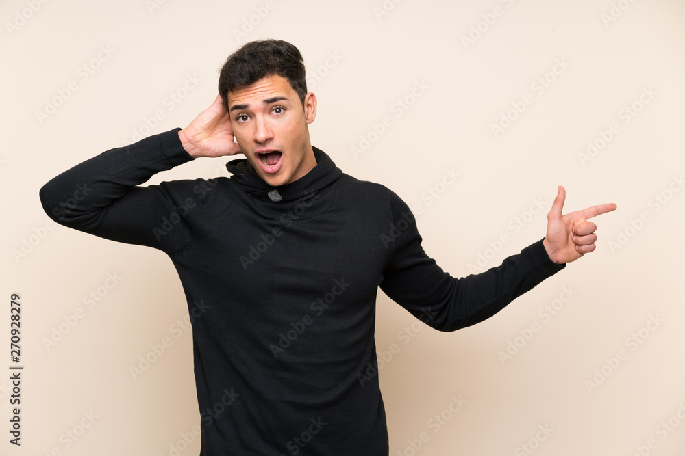 Handsome man over isolated background surprised and pointing finger to the side Handsome man over isolated background surprised and pointing finger to the side