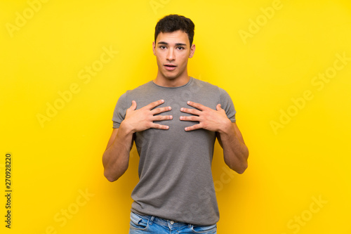Handsome man over isolated yellow wall surprised and shocked while looking right