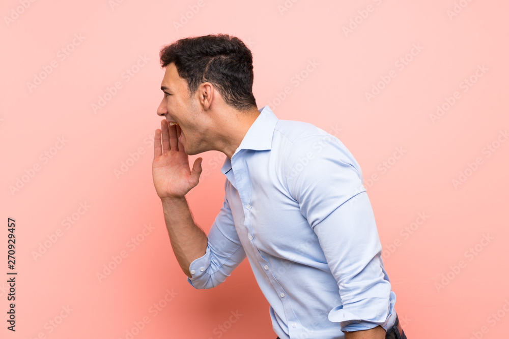 Handsome man over pink background shouting with mouth wide open to the lateral Handsome man over pink background shouting with mouth wide open to the lateral