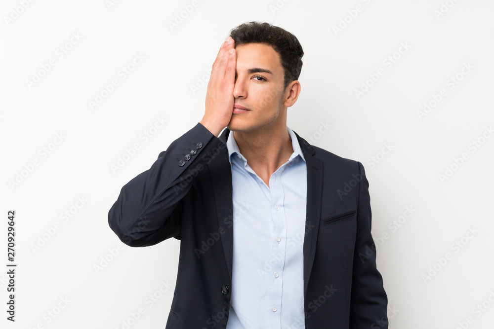 Handsome man over isolated white wall covering a eye by hand Handsome man over isolated white wall covering a eye by hand