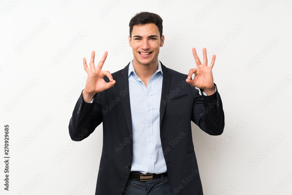 Handsome man over isolated white wall showing an ok sign with fingers Handsome man over isolated white wall showing an ok sign with fingers
