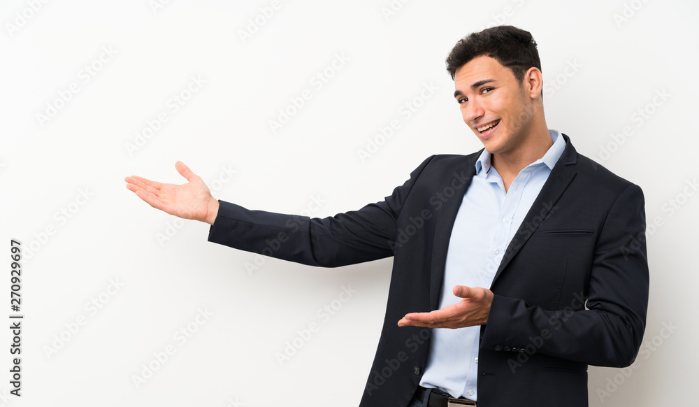 Handsome man over isolated white wall extending hands to the side for inviting to come Handsome man over isolated white wall extending hands to the side for inviting to come