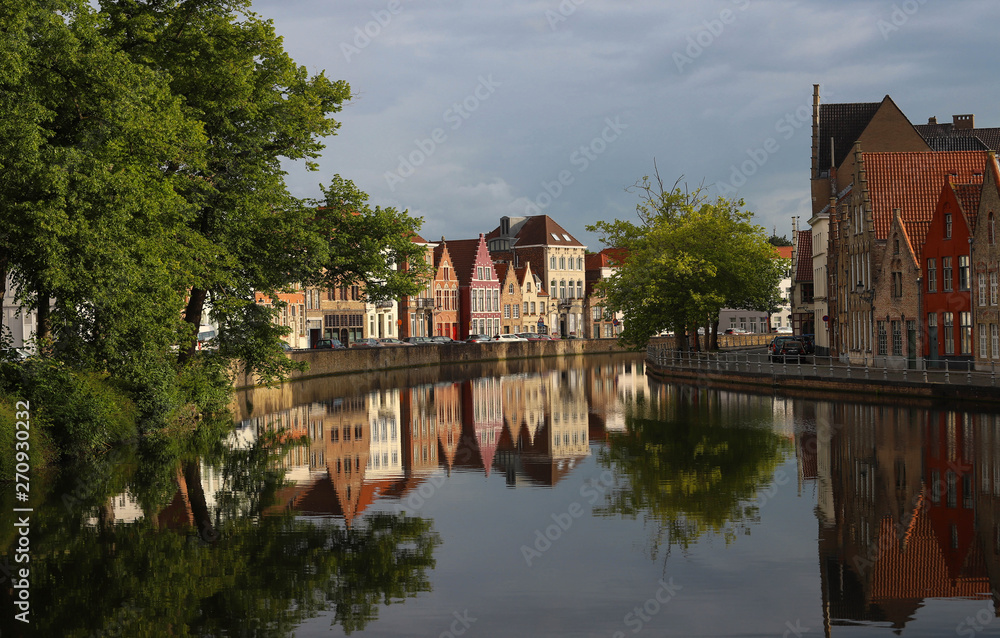 Scenic city view of Bruges canal with beautiful medieval colored houses, bridge and reflections at sunny day.