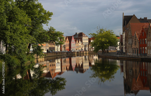 Scenic city view of Bruges canal with beautiful medieval colored houses, bridge and reflections at sunny day.