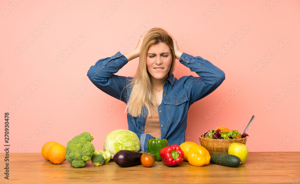 Young blonde woman with many vegetables frustrated and takes hands on head Young blonde woman with many vegetables frustrated and takes hands on head