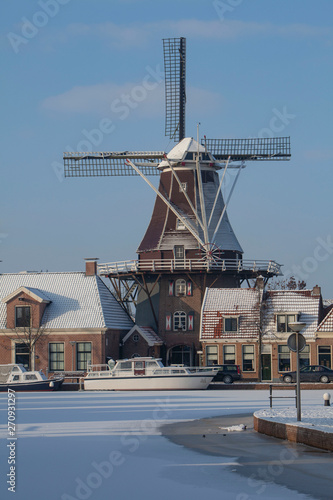 Traditional windmill in winter Meppel Drenthe Netherlands. Frozen canal Sluisgracht. Stoombootkade.