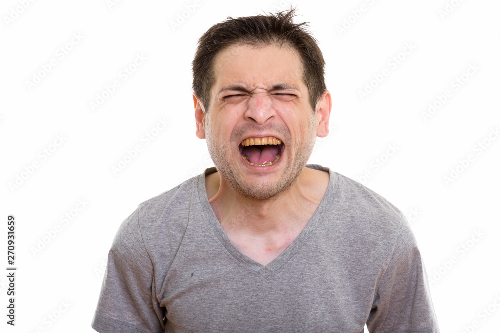 Studio shot of angry young man screaming with eyes closed Studio shot of angry young man screaming with eyes closed