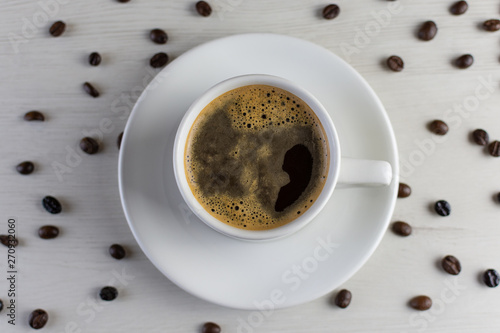 View from above of a delicious and tasty cup of freshly made coffee with coffee beans