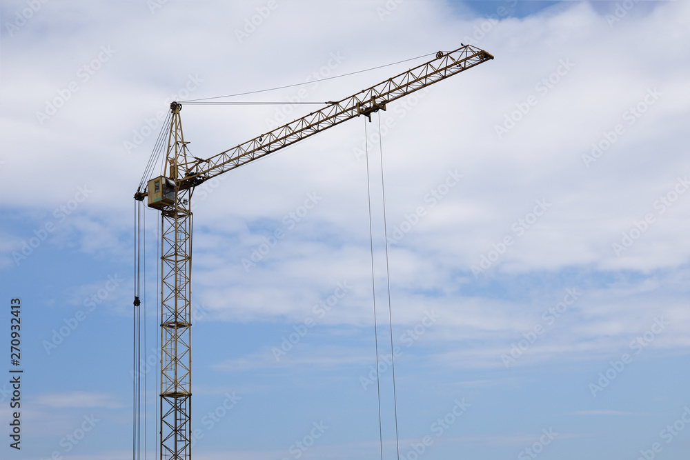 Industrial construction building crane against blue cloudy sky Industrial construction building crane against blue cloudy sky