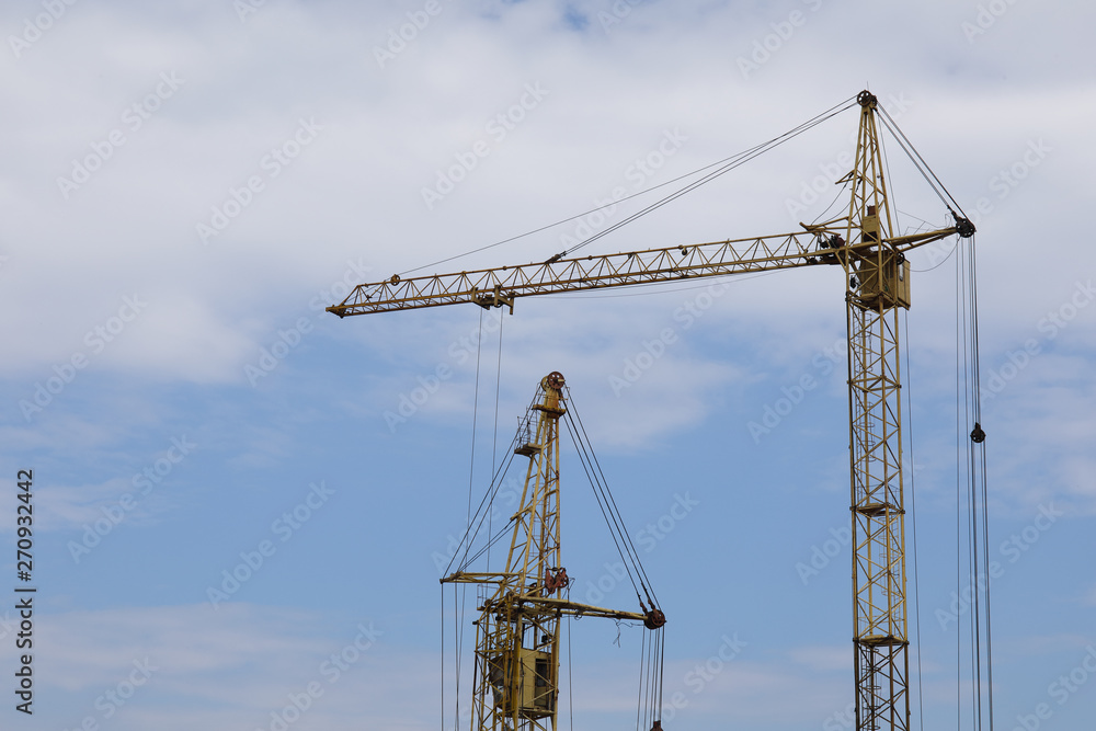 Industrial construction building cranes against blue cloudy sky