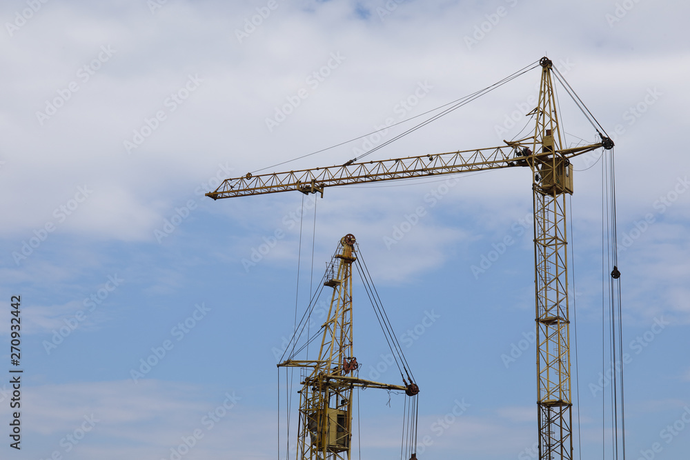 Industrial construction building cranes against blue cloudy sky Industrial construction building cranes against blue cloudy sky