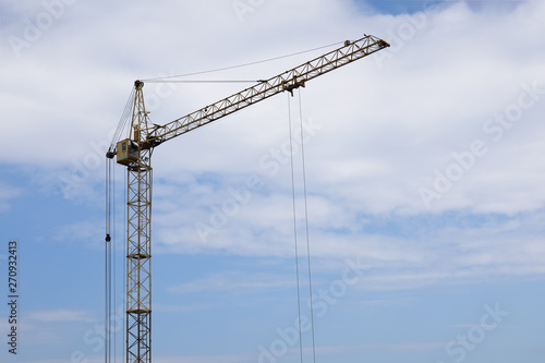 Industrial construction building crane against blue cloudy sky
