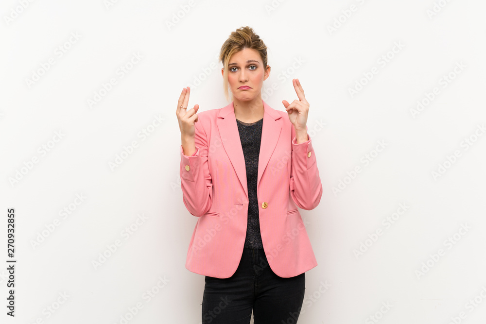 Young blonde woman with pink suit with fingers crossing and wishing the best Young blonde woman with pink suit with fingers crossing and wishing the best
