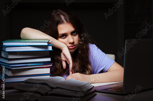 Young female student preparing for exams late at home 