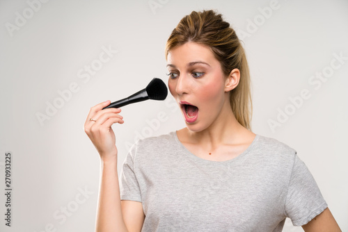 Young blonde woman with makeup brush