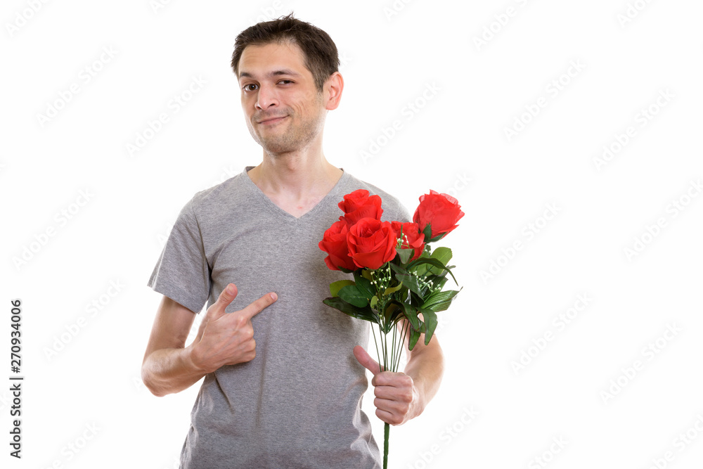 Studio shot of young man holding and pointing at red roses ready Studio shot of young man holding and pointing at red roses ready